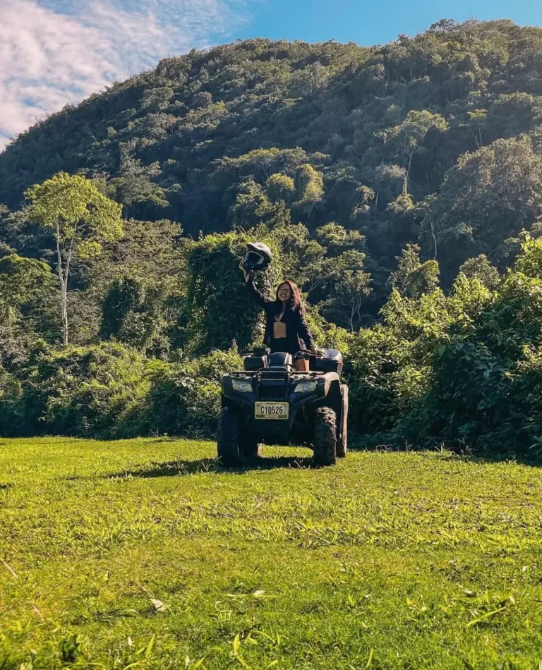 woman on atv raising helmet in one hand