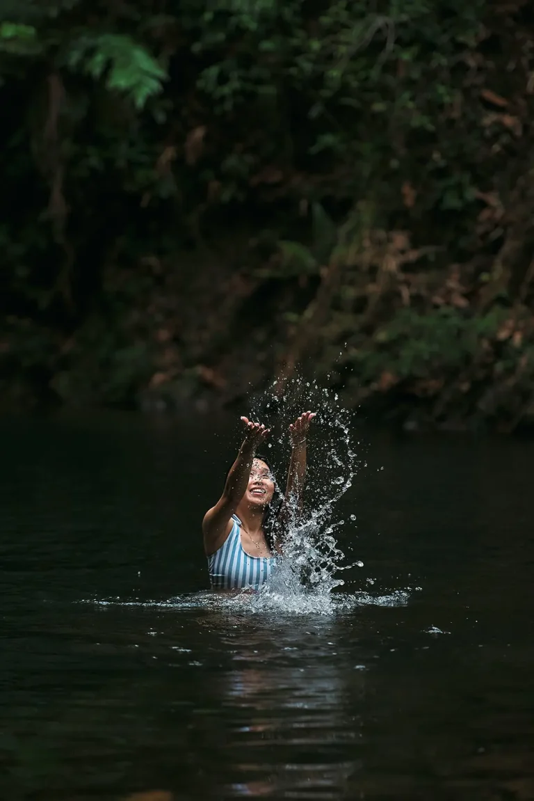 woman splashing water at waterfall in belize