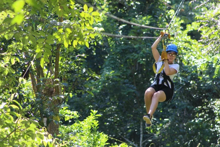 woman ziplining through forest with helmet